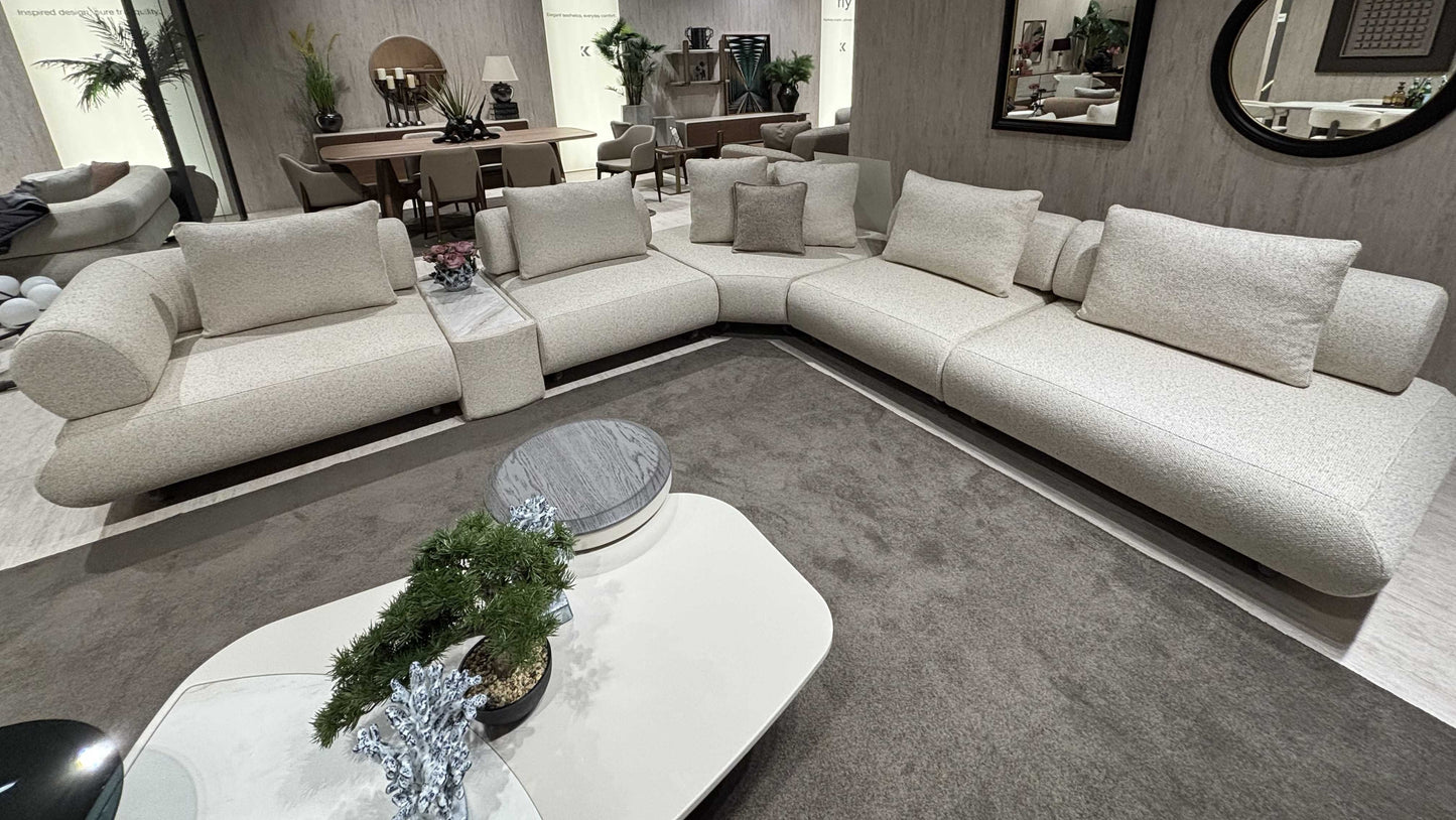 Salon moderne avec canapé Hermes en L, tables basses design et décoration élégante, ambiance chaleureuse et raffinée